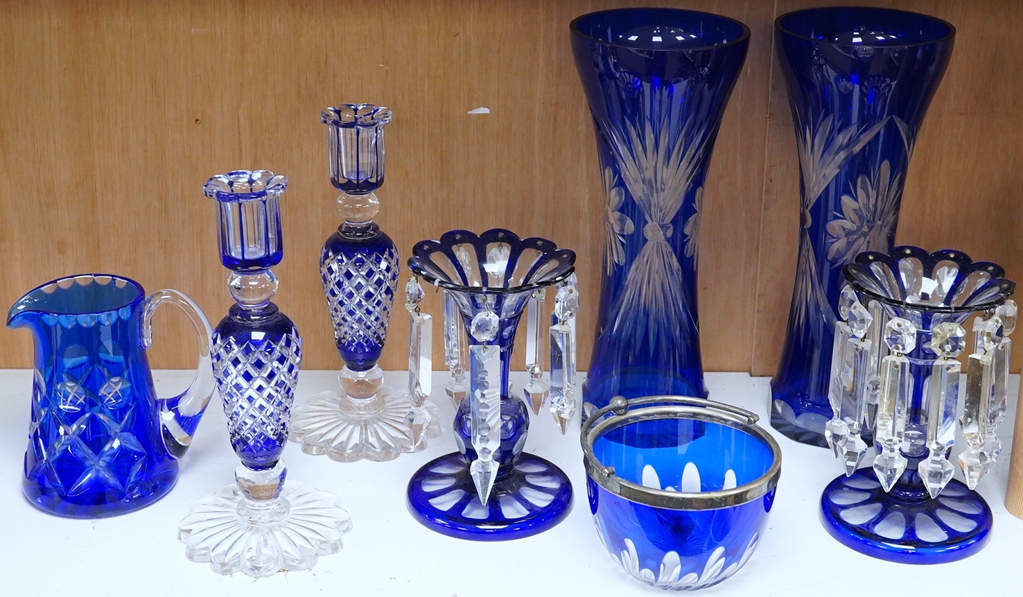 A pair of blue overlaid glass table lustres with drops and other blue overlaid glassware to include a pair of candlesticks and vases, largest 27cm high